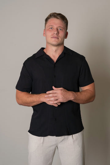 "Close-up of Men’s Black Cuban Short Sleeve Shirt fabric, showing premium lightweight material, button details, Cuban collar, and abstract white print. Modern tailored fit for men."