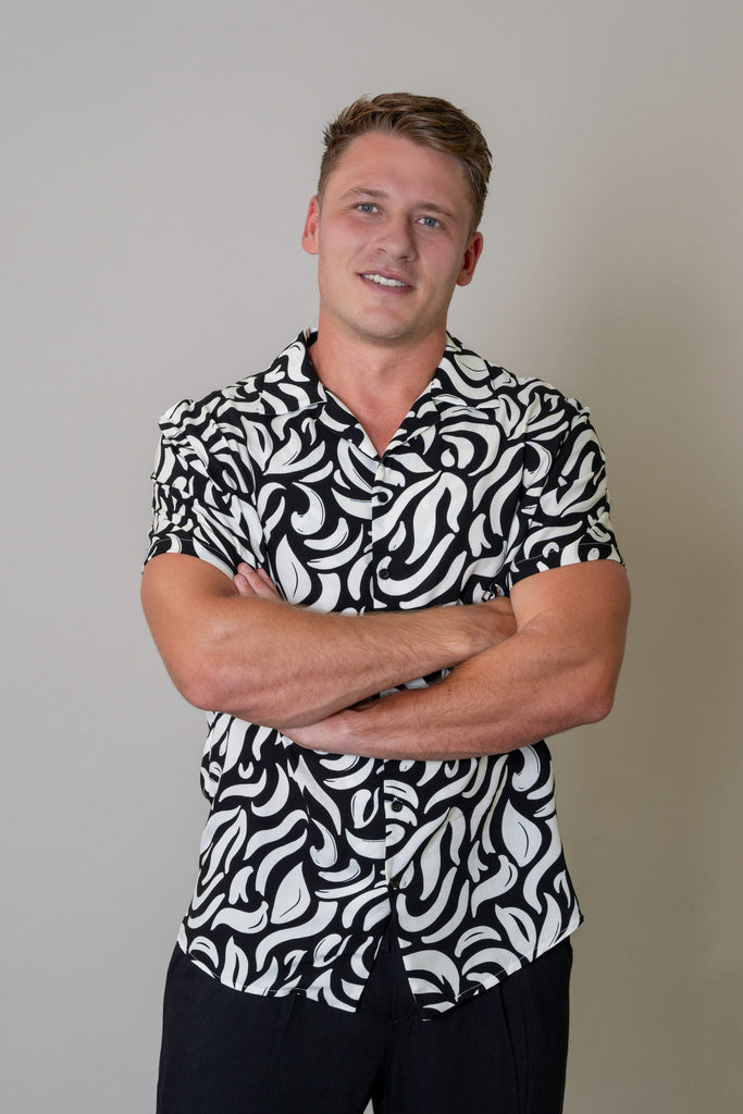 Black Cuban Short Sleeve Shirt for men with white geometric print, button-up front, Cuban collar, short sleeves, and curved hem. Smart casual summer shirt, lightweight and breathable fabric.