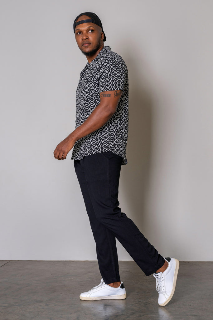 Black Retro Cuban Short Sleeve Shirt for men with white geometric print, button-up front, Cuban collar, short sleeves, and curved hem. Smart casual summer shirt, lightweight and breathable fabric.