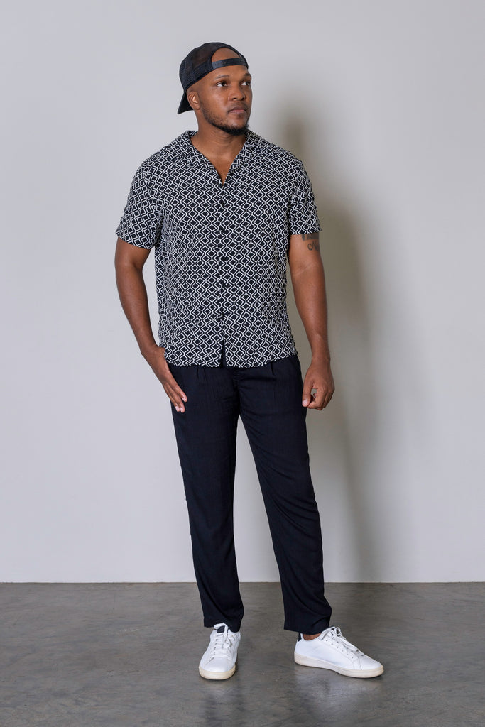 Black Retro Cuban Short Sleeve Shirt for men with white geometric print, button-up front, Cuban collar, short sleeves, and curved hem. Smart casual summer shirt, lightweight and breathable fabric.