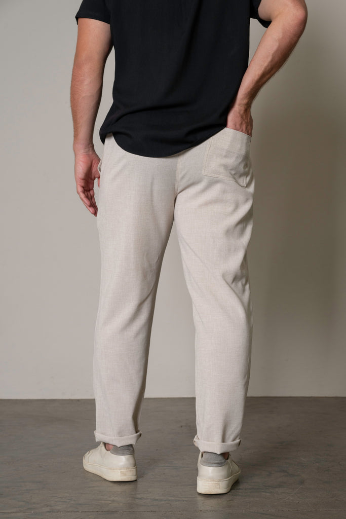 "Back view of men's lightweight tailored drawstring trousers in sand beige, showcasing the clean, minimalist design and tailored fit. The smooth finish and practical drawstring waist create a refined look for any occasion."